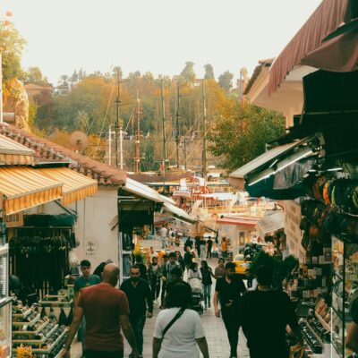 Vibrant street market scene with people walking along shops during the day.